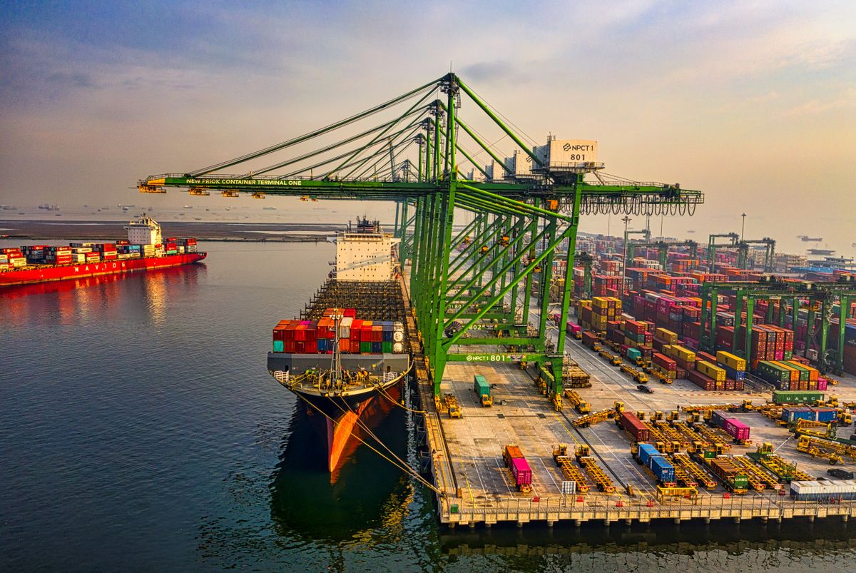 Container ship berthed under green gantry cranes at a container terminal